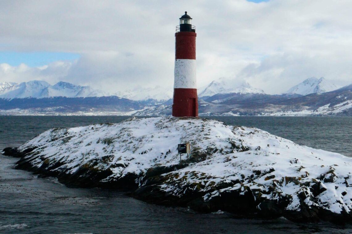 Faro con nieve y montañas de fondo